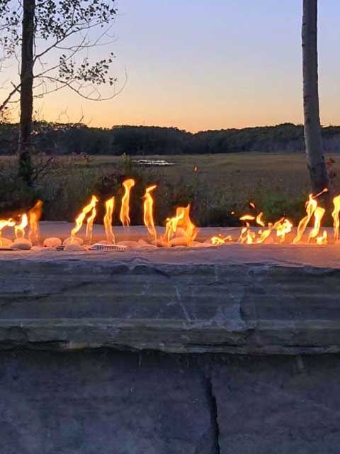 close up view of a gas fire pit insert overlooking the marsh in wells maine