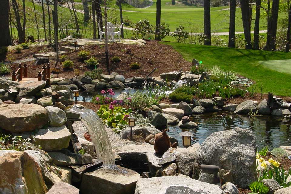 large landscaped pond and plantings enhance the front yard